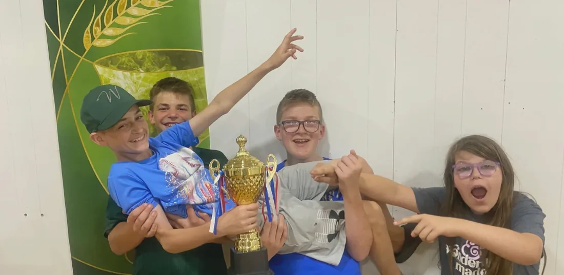 Four students cheering with a gold trophy