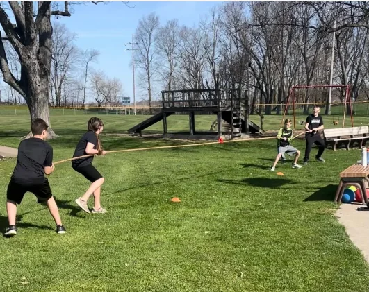 Students playing tug-of-war on the grass during gym class