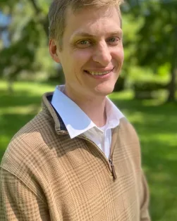 Headmaster Nathan Collins smiling outdoors on a sunny day