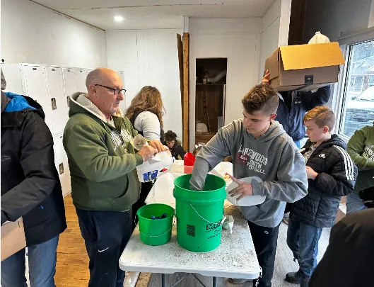 Students and adults filling buckets together during a service project